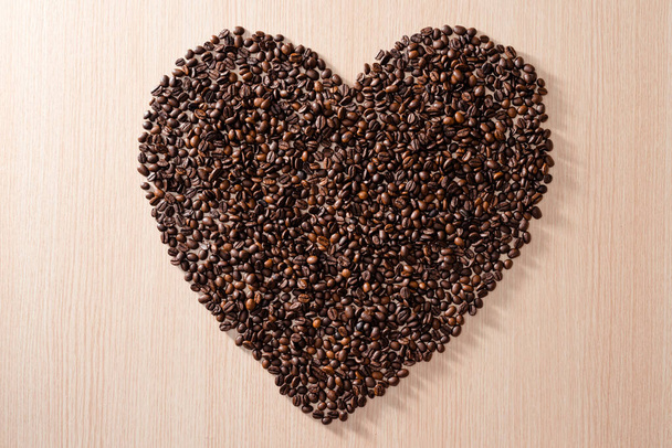 heart shape made of coffee beans on wooden background - 写真・画像