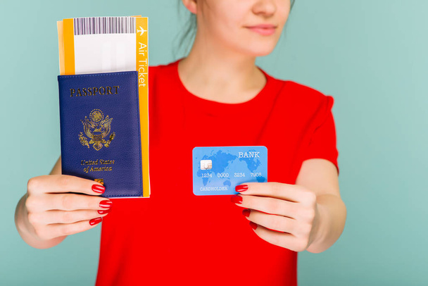 Jovem sorrindo estudante segurando passaporte bilhete de passagem e cartão de crédito isolado em fundo azul
. - Foto, Imagem