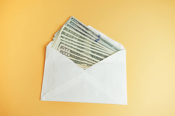Κοντινό πλάνο Όμορφα δολάρια στο φάκελο σε κίτρινο φόντο. Αμερικάνος, δολάρια μετρητά. Τραπεζογραμμάτια των εκατό δολαρίων . - Φωτογραφία, εικόνα