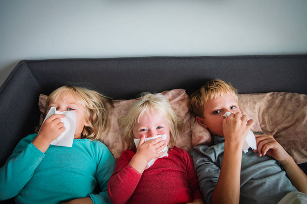 kids wiping and blowing nose in bed, infection or allergy - Photo, Image