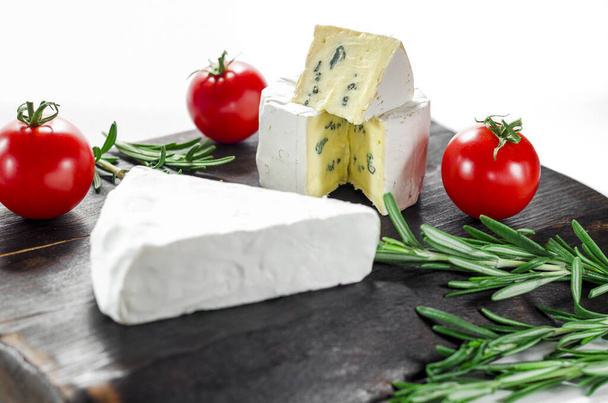 Асорті сирів на дерев'яній дошці. Камамбер, сир з синьою цвіллю, моцарелла з помідорами
 - Фото, зображення