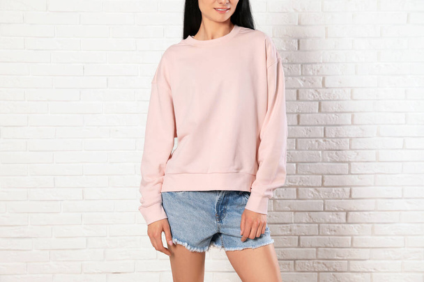 Young woman in sweater at brick wall, closeup. Mock up for design - Φωτογραφία, εικόνα