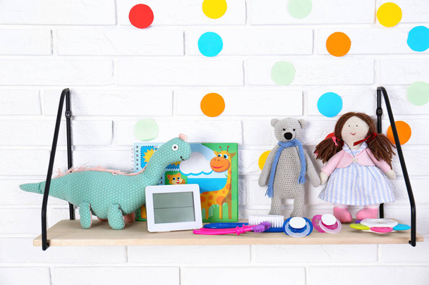 Baby accessories on shelf near white brick wall - Photo, Image