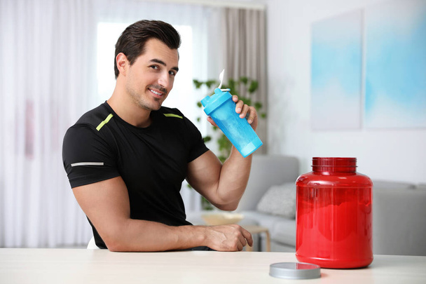 Young athletic man with protein shake at home - Foto, Bild