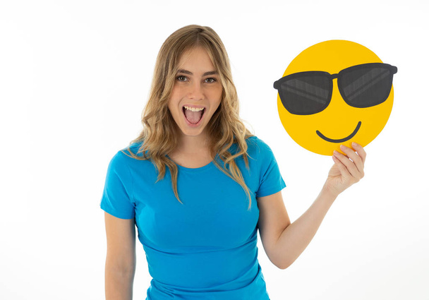 Attractive and fashion teenager woman holding cool face emoji social media notification icon in trends, facial expressions and social network notification icons and technology communication. - 写真・画像