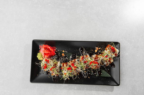 Philadelphia roll sushi with eel, avocado, cream cheese and caviar. Sushi menu. On dark stone plate in white background. Traditional japanese seafood, healthy food concept. Horizontal photo. - Photo, image