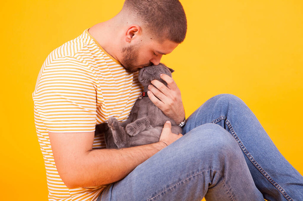 Yakışıklı genç adam kedisini öpüyor ve sevgisini gösteriyor. - Fotoğraf, Görsel