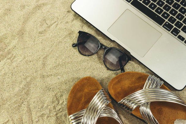 Laptop, Sonnenbrille und Sommerschuhe auf Sand, Sommerkonzept - Foto, Bild