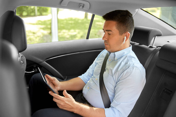 passenger with earphones and tablet pc in taxi car - Foto, afbeelding