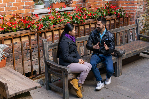 Молодые мужчина и женщина весело обсуждают что-то, в то время как они сидят за одним столом.
 - Фото, изображение