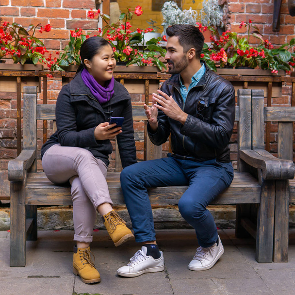 Evropan mladý muž mluví s asijské dívka drží smartphone - Fotografie, Obrázek