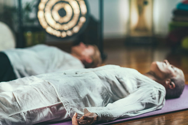 ガイド付き瞑想療法。年配の女性が瞑想して床に横になって - 写真・画像