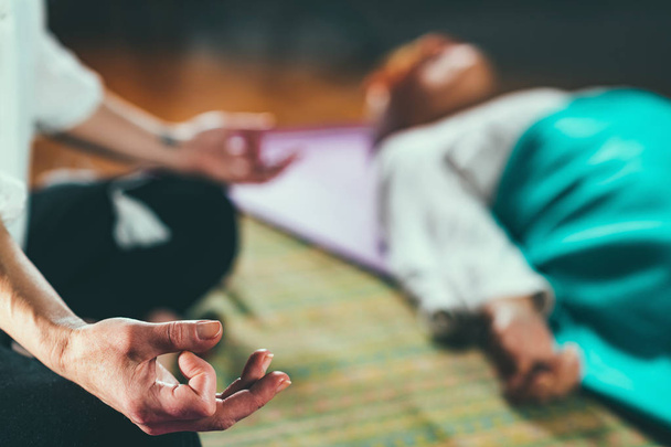 瞑想のガイド。床に寝そべって瞑想するシニア女性とミッド大人の女性 - 写真・画像