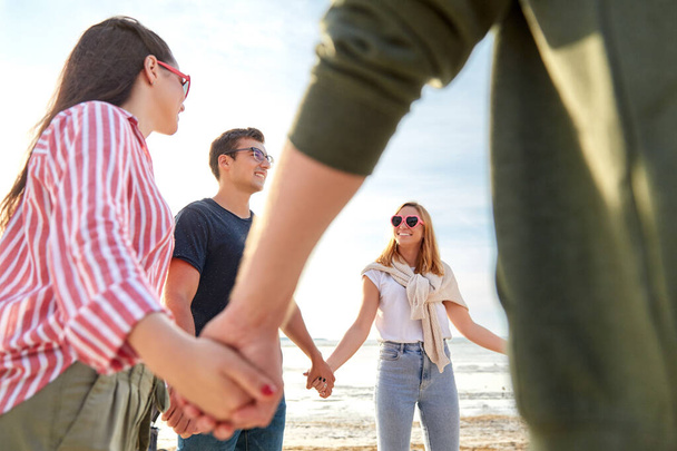 boldog barátok kéz a kézben a nyári strandon - Fotó, kép