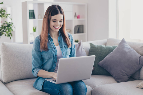 Photo of pretty lady holding notebook on knees working at home speaking skype with colleagues sitting comfy on sofa wearing jeans outfit apartment indoors - Fotoğraf, Görsel