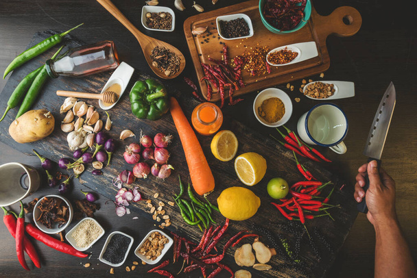 健康的な食品ハーブ木の上に新鮮な有機野菜と木製の背景に調理材料として使用するためのスパイス。素朴なテーブルの上にバラエティ豊かな食材のコンセプト. - 写真・画像