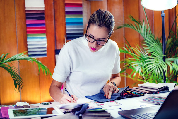 Dekorateurin betrachtet Stoffmuster in ihrem Büro - Foto, Bild