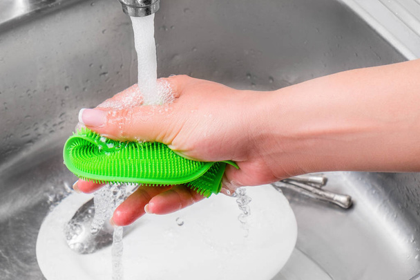 Immagine ritagliata di attraente giovane donna sta lavando i piatti mentre
  - Foto, immagini