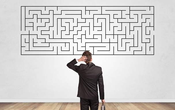 Businessman looking to a maze on a wall - Foto, Imagen