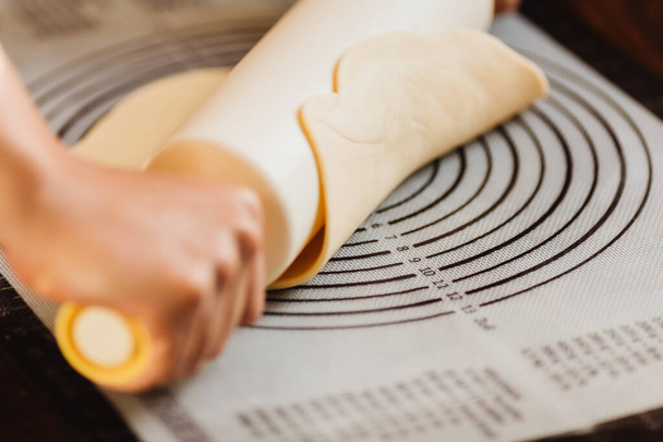 Vrouwelijke chef kok handen deeg deeg met pin op siliconen bakmat - Foto, afbeelding
