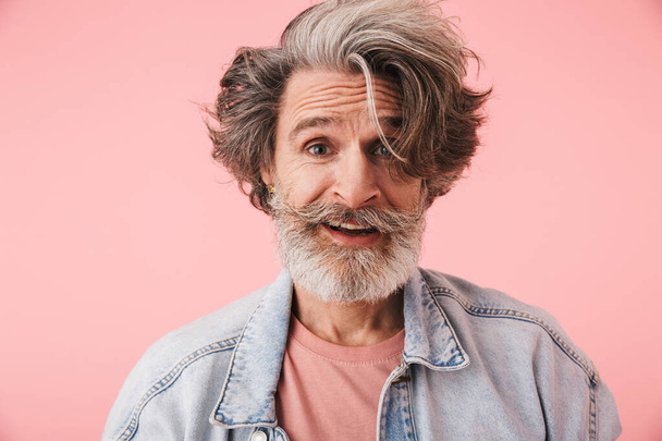 Portrait closeup of pleased mature man 70s with gray beard and messy hair smiling at camera - Foto, Imagen