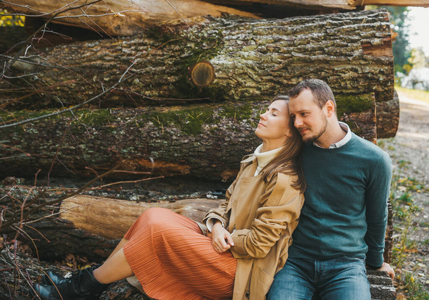 Loving couple sitting on the felled logs in the forest. Man and woman embracing. love story. - Foto, afbeelding