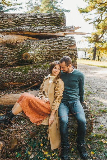 Pretty young couple outdoor on the wooden logs in autumn forest - Fotografie, Obrázek