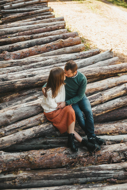 Ζευγάρι ερωτευμένο να αγκαλιάζει τους υλοτομημένους κορμούς στο δάσος. Άνδρας και γυναίκα αγκαλιάζουν.  - Φωτογραφία, εικόνα