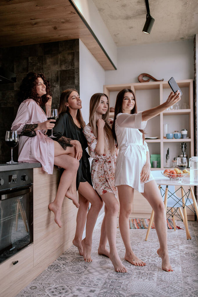 zufriedene Mädchen im Schlafanzug, die Spaß in der Küche haben, fröhliche junge Dame, die morgens mit Freunden Selfie macht - Foto, Bild