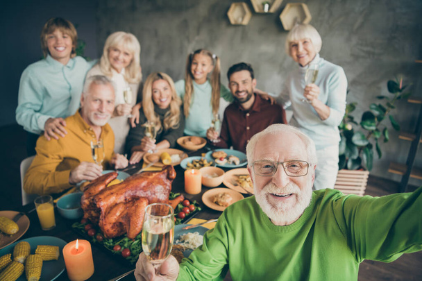 Photo of big family sit hugging feast dishes table around roasted turkey multi-generation relatives making group selfies raising wine glasses in living room indoors - Foto, Imagen