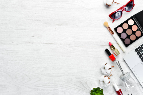 Female cosmetics on white office desk. Laptop, notepad, Lipstick, powder, comb, women's jewelry. Top view. Free space for your text. Flat lay. - Fotó, kép