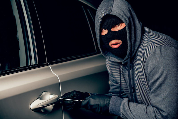 A man with a Balaclava on his head tried to break into the car.  - Photo, Image