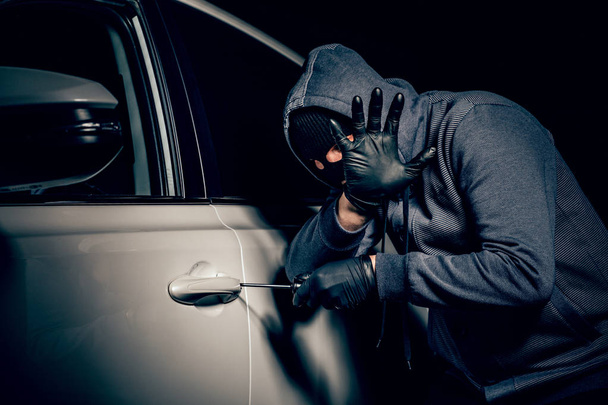A man with a Balaclava on his head tried to break into the car.  - Photo, Image