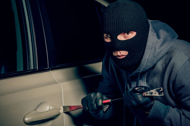 voleur masculin va ouvrir la porte de la voiture avec un pied-de-biche
. - Photo, image