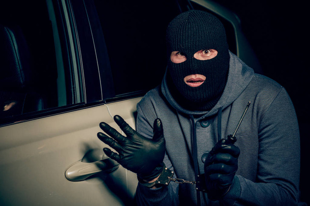 A man with a Balaclava on his head tried to break into the car.  - Photo, image