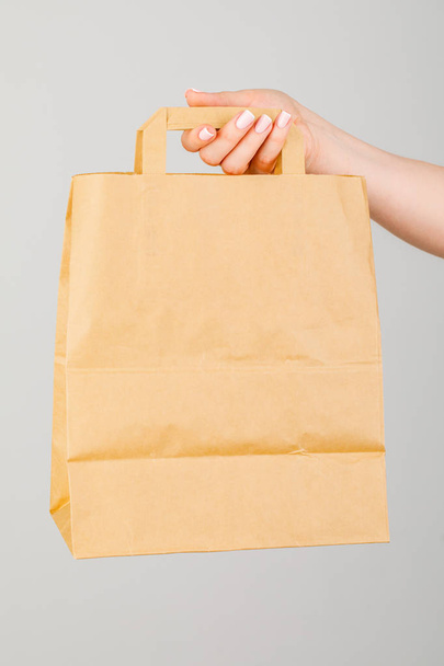 Крупный план женщины, держащей коричневый пустой бумажный пакет, изолированный на Уит
 - Фото, изображение