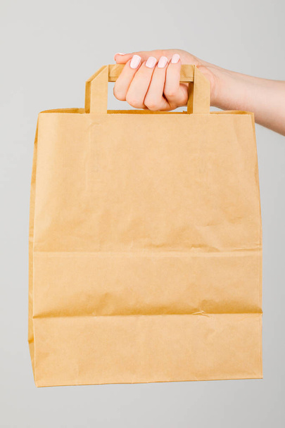 Close-up of woman holding brown empty paper bag isolated on whit - Foto, Imagem