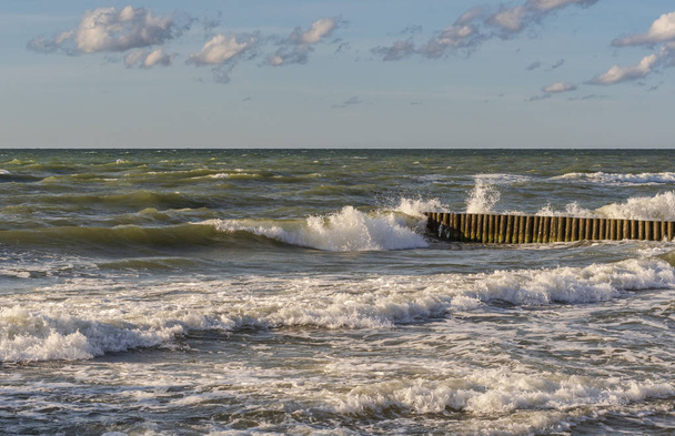 Rompeolas luchando con grandes olas en tiempo ventoso
 - Foto, imagen