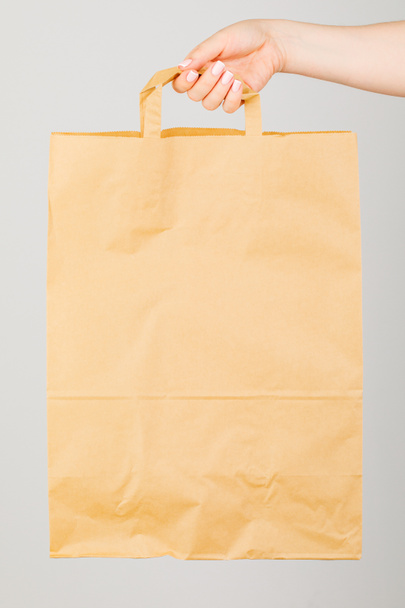 Закрытие - женщина держит коричневый пустой бумажный пакет в изоляции.
 - Фото, изображение