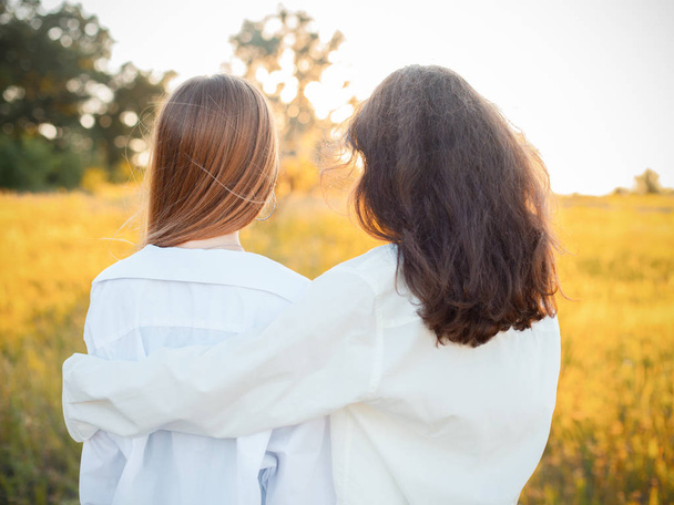 Две молодые женщины в белых рубашках, смотрящие на закат. Лучшие друзья
 - Фото, изображение