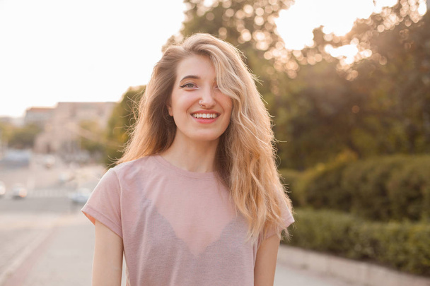 Şehirde güneş ışığı altında mutlu genç bir kadının portresi. - Fotoğraf, Görsel
