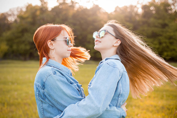 Two happy young women having fun outdoors under sunlight. Best friends - Фото, изображение