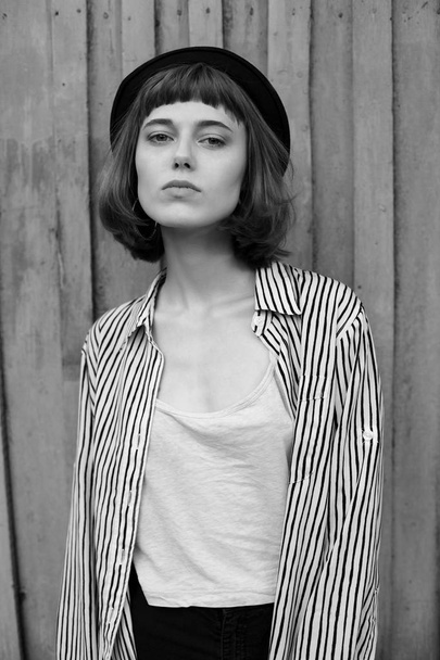 Portrait of fashionable young woman near wooden wall. Black and white - Foto, Imagen