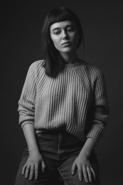 Studio portrait of young woman in sweater. Black and white - Valokuva, kuva