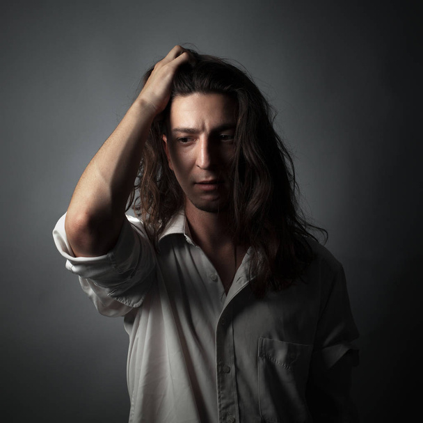 Worried young man on gray background. Studio portrait - Foto, imagen