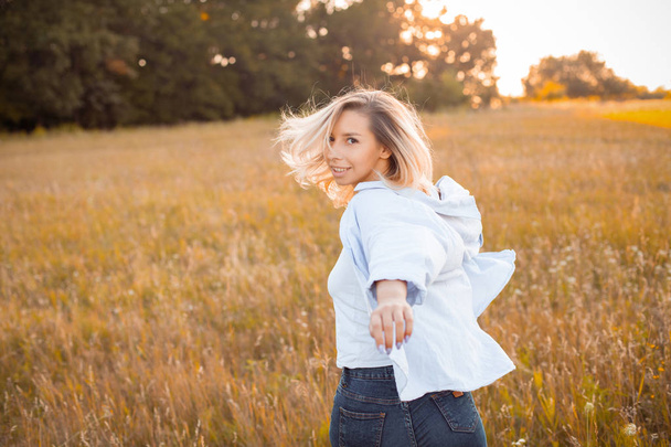 Nuori aktiivinen nainen paidassa kävelee ulkona auringonlaskun aikaan. Käänny ympäri.
 - Valokuva, kuva