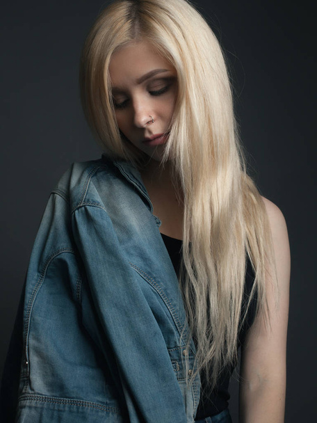 Portrait of young woman with beautiful long hair covered by jean jacket - Photo, image