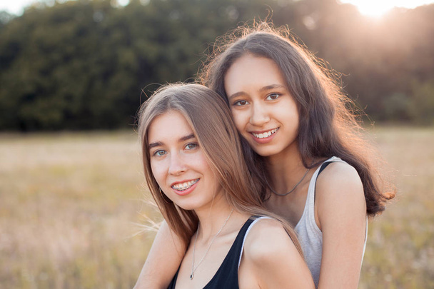 zwei glückliche junge Frauen, die sich bei Sonnenuntergang im Freien umarmen. beste Freunde - Foto, Bild