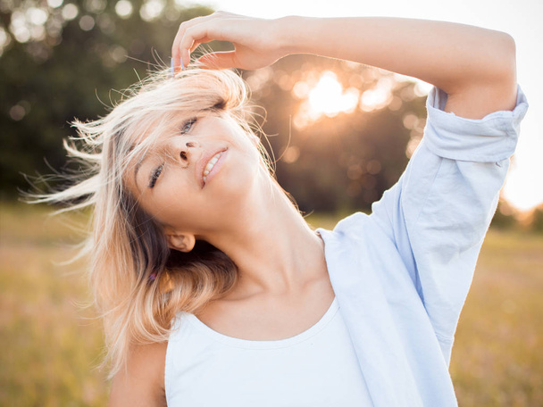 Young blonde woman having fun outdoors at sunset. - Fotoğraf, Görsel