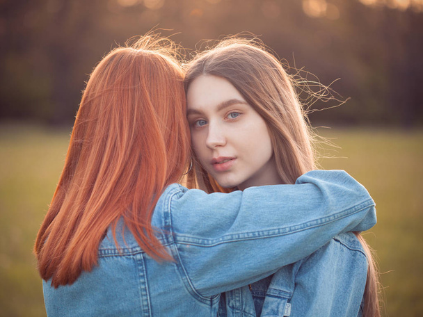 Two young women hugging outdoors at sunset. Best friends - Foto, afbeelding